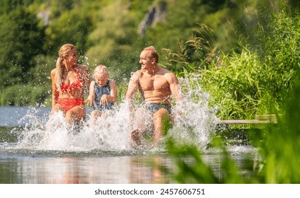 family of three, two adults and a child, joyfully splashing water while sitting on a lakeside dock in germany - Powered by Shutterstock