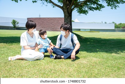 Family Of Three Wearing Masks In The Park