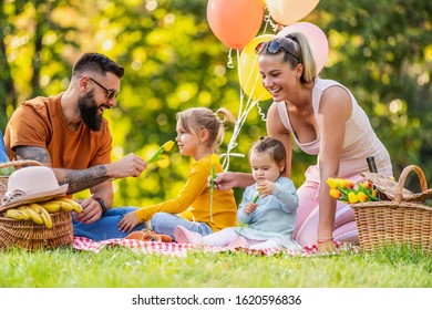 Family Time In Countryside.Cheerful Family Sitting On The Grass During A Picnic In The Park.