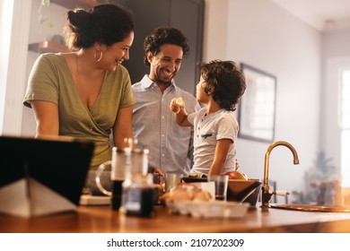 Family time in the kitchen. Happy young boy eating a banana while sitting on a kitchen counter. Mom and dad smiling happily while spending quality time with their son at home. - Powered by Shutterstock