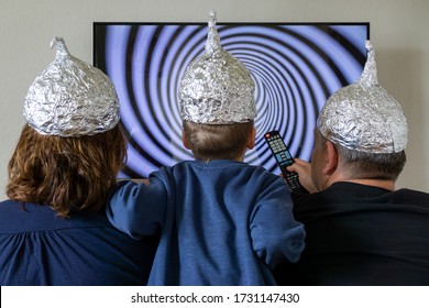 Family With Tin Foil Hat In Front Of TV