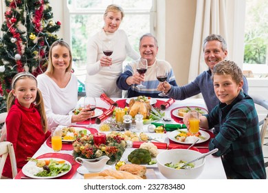Family toasting at camera with red wine at home in the living room