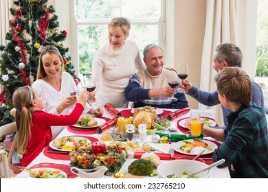 Family Toasting With Red Wine In A Christmas Dinner At Home In The Living Room