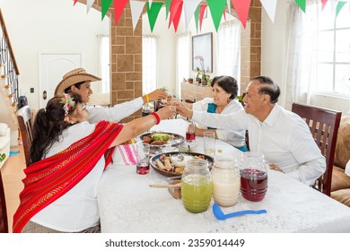 Family toasts with tequila sitting at the table during a meal to celebrate the Mexican national holidays. Members of a family toast with tequila horses during the celebration of Mexican independence. - Powered by Shutterstock