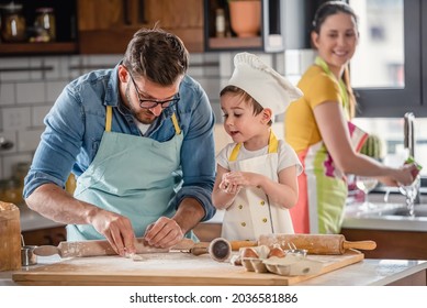 Family together in the kitchen. Father making cake with his toddler son. Happy mother is doing dishes. Father's day. Mother's Day.