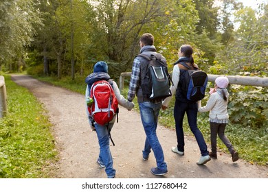 Family, Tourism And Hiking Concept - Happy Mother, Father, Son And Daughter With Backpacks Walking In Woods