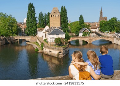 A family of tourists looks on Bridge Ponts Couverts de Strasbourg, Strasbourg, Alsace, France. Canals district La Petite France in Strasbourg in summer.