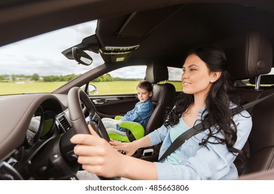 Family, Transport, Road Trip And People Concept - Happy Woman With Little Daughter Driving In Car