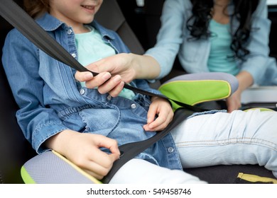 family, transport, road trip and people concept - happy woman fastening child with safety seat belt in car