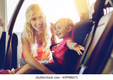 Family, Transport, Safety, Road Trip And People Concept - Happy Mother Fastening Child With Car Seat Belt