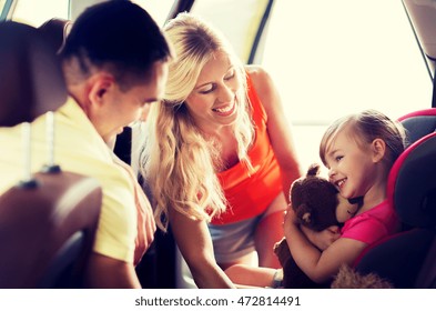 Family, Transport, Safety, Road Trip And People Concept - Happy Parents With To Little Girl In Baby Car Seat Hugging Teddy Bear Toy