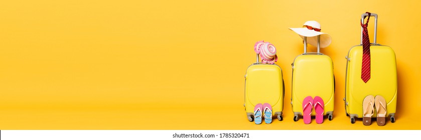 family travel bags with beach summer accessories isolated on yellow, panoramic shot