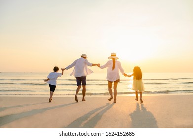 Family, travel, beach, relax, lifestyle, holiday concept. Family who enjoy a picnic. Parents are holding hands their children and walking on the beach at sunset in holiday. 
