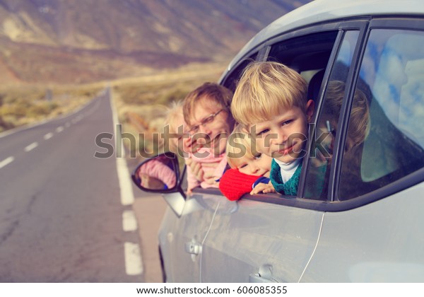family travel by car- happy father with kids on\
road in mountains