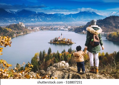 Family Travel Europe. Mother With Son Looking On Bled Lake. Autumn Or Winter In Slovenia, Europe. Top View On Island With Catholic Church In Bled Lake With Castle And Mountains In Background.