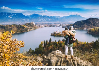 Family Travel Europe. Mother With Son Looking On Bled Lake. Autumn Or Winter In Slovenia, Europe. Top View On Island With Catholic Church In Bled Lake With Castle And Mountains In Background.