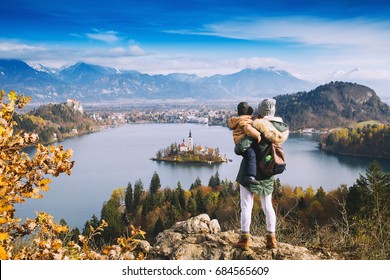 Family Travel Europe. Mother With Son Looking On Bled Lake. Autumn Or Winter In Slovenia, Europe. Top View On Island With Catholic Church In Bled Lake With Castle And Mountains In Background.