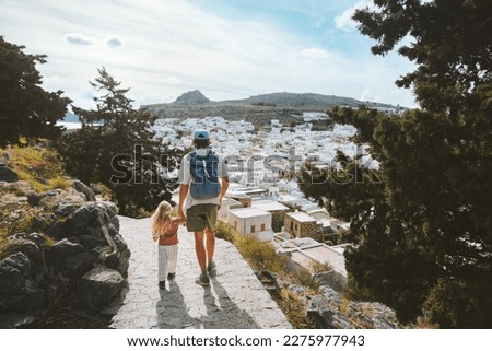 Family travel in Greece father and child sightseeing Rhodes island Lindos city white houses aerial view architecture landmarks summer vacations lifestyle man with daughter walking together