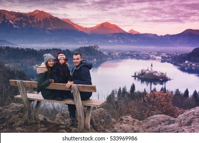 Family Travel Slovenia, Europe. Bled Lake One Of Most Amazing Tourist Attractions. Winter Landscape. Top View On Island With Catholic Church In Bled Lake With Castle And Alps Mountains In Background.