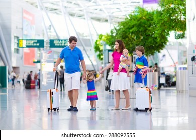 Family Traveling With Kids. Parents With Children At International Airport With Luggage. Mother And Father Hold Baby, Toddler Girl And Boy Flying By Airplane. Travel With Child For Summer Vacation.