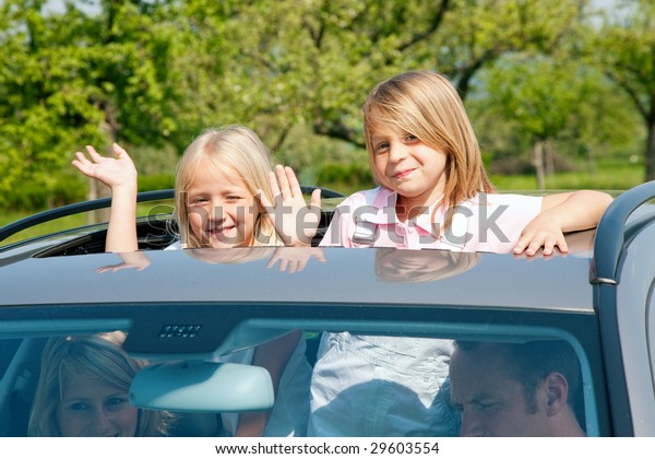 Family\
travelling by car, kids waving their\
hands