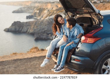 Family trip to the mountains by car. Mom is having fun with her teenage son, sitting in the trunk of a car and enjoying the view together. - Powered by Shutterstock