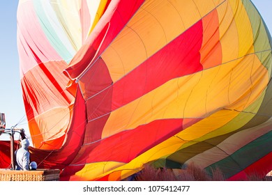 Family Of Two In The Basket Looking At Hot Air Baloon Filling Up With Air Ready For Take Off, Adventure Vacation Concept