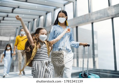 Family With Two Children Going On Holiday, Wearing Face Masks At The Airport.