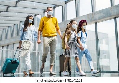 Family With Two Children Going On Holiday, Wearing Face Masks At The Airport.