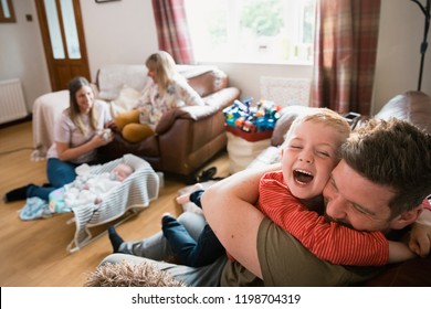 Family with two children and their grandmother sitting in the living room on sofas. They are relaxing, watching the tv and talking. The grandmother has come to visit her newborn grandson. - Powered by Shutterstock