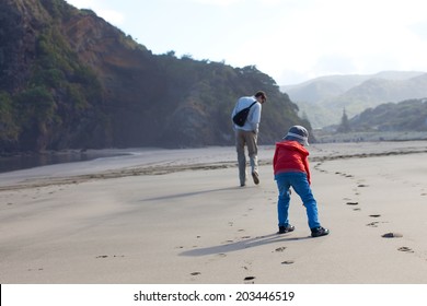 family of two having fun at piha beach, new zealand