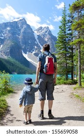 Family Of Two Hiking By Lake Moraine In Banff National Park, Alberta, Canada