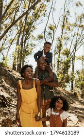 Family With Two Kids On A Mountain Trail. Family Hiking Through Forest And Smiling.