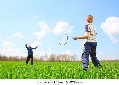 Family - two little boys playing badminton on green meadow