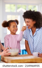 Family With Two Mums Wearing Pyjamas Making Morning Pancakes In Kitchen At Home With Daughter