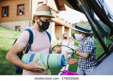 Family with two small children loading car for trip in countryside, wearing face masks. - Powered by Shutterstock