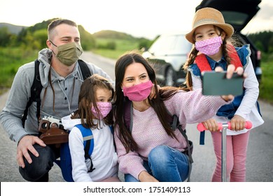 Family with two small daughters and face masks on trip outdoors in nature, taking selfie. - Powered by Shutterstock