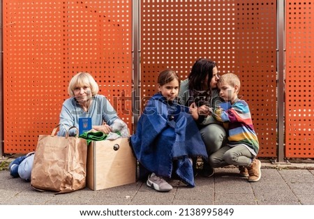 Family of Ukrainian refugees with children and pet cat holding passports fleeing from Ukraine waiting for help and registration in charity center. Text on passports is: Ukraine Passport Stockfoto © 