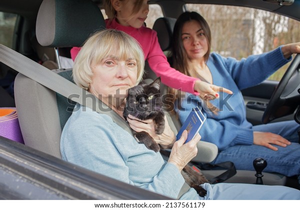 Family\
of Ukrainian refugees, seniors, woman and kids, fleeing from war\
against Russia and cross the board by car together with pet. World\
terrorism and war. Volunteering and helping\
hand