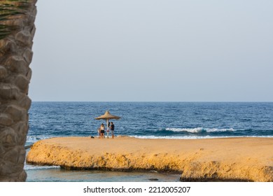 Family Under A Single Beach Umbrella On A Bay At The Sea In Egypt