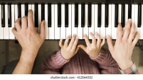 Family Unity Concept Image - Piano Keyboard top View and Hands of Child Mother and Father playing music