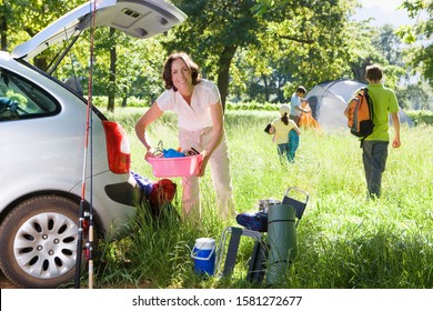 Family unload camping equipment and tent from car boot in countryside - Powered by Shutterstock