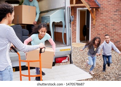 Family Unloading Furniture From Removal Truck Into New Home