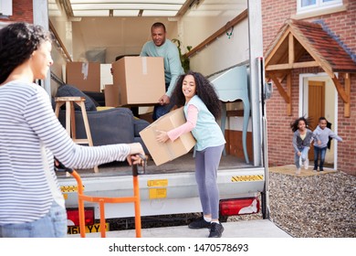 Family Unloading Furniture From Removal Truck Into New Home