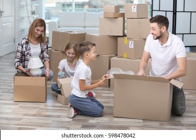 Family unpacking cardboard boxes in new home