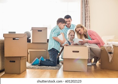 Family Unpacking Cardboard Boxes At New Home