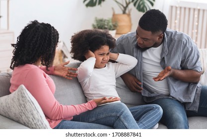 Family Upbringing Concept. Small african kid girl covering ears not to listen parents scolding, disobedient child ignoring father's words - Powered by Shutterstock