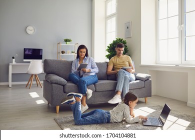 Family Uses Gadgets In The Living Room.