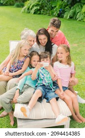 Family Using Cell Phone Together In Backyard