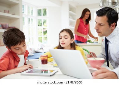 Family Using Digital Devices At Breakfast Table